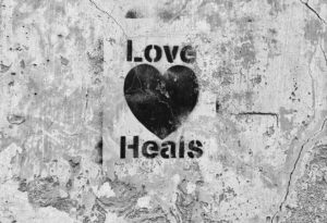 cement wall with stencil "love heals" and a heart 