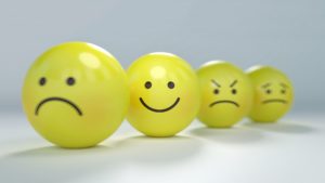 four yellow balls with sad, happy, angry, and worried faces 