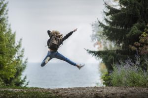 woman with backpack jumping for joy