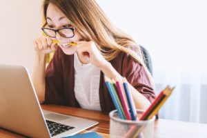 woman looking at computer biting a pencil 