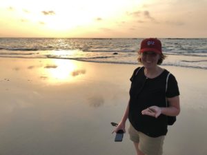 woman on the beach at sunset holding seashells 