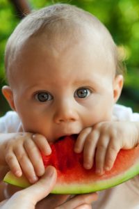 wide eyed baby trying watermelon for the first time
