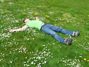 man laying flat in grass with flowers