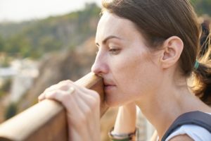 tired woman leaning on a railing looking at a view