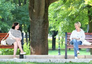 two women on different park benches talking