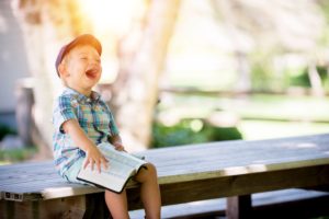 a child on a bench with a book laughing