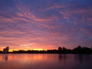 blue, pink, orange, and yellow sunset over a still lake