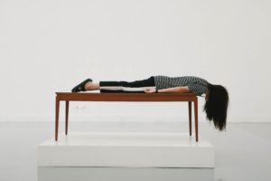 woman laying flat on stomach on a table in a white room 