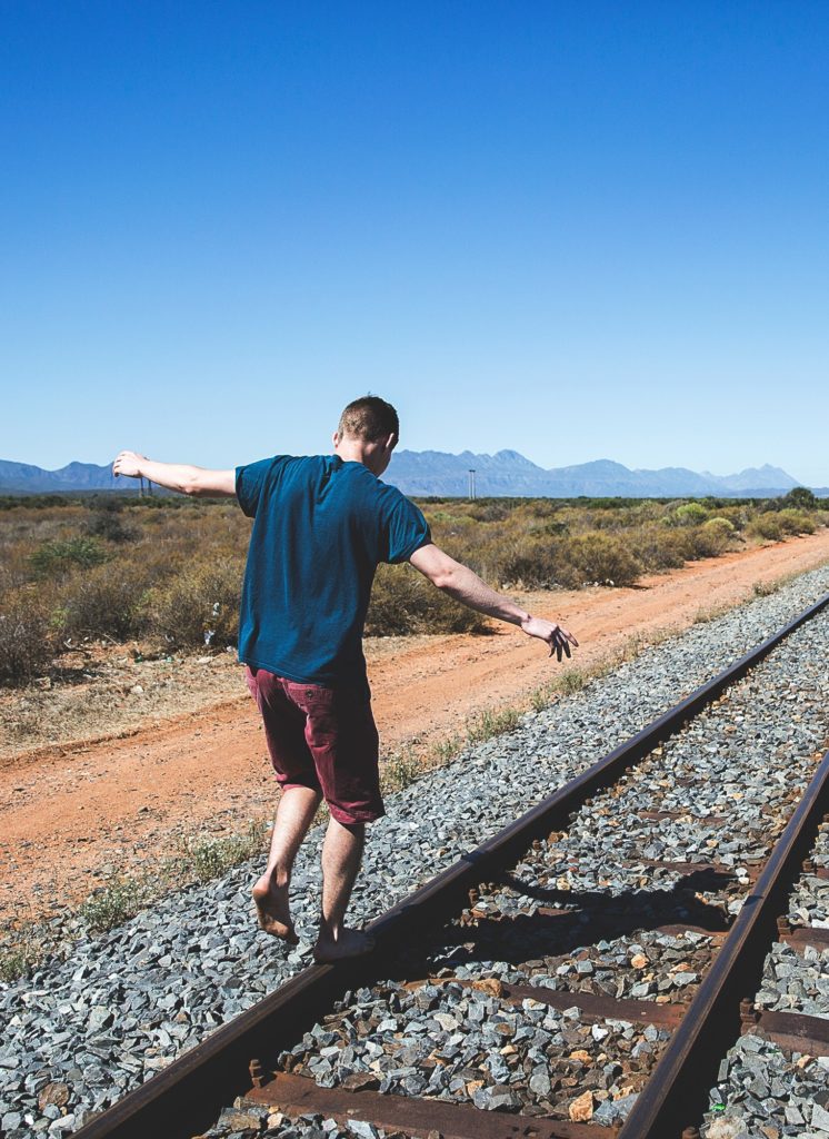 man balancing on a train track to represent the life balance you can reach through narcolepsy coaching