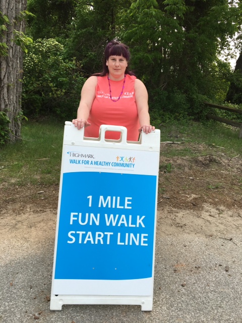 Jill Hetrick stands by the sign for the Erie Highmark Walk