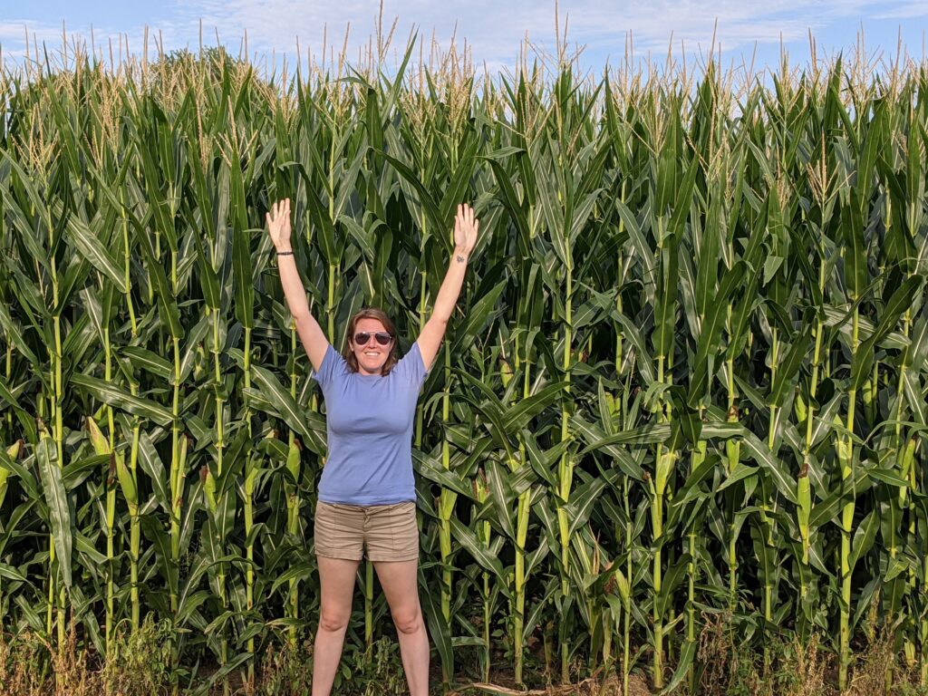 me standing next to some super tall corn stretching my arms to show I cannot reach the top! 