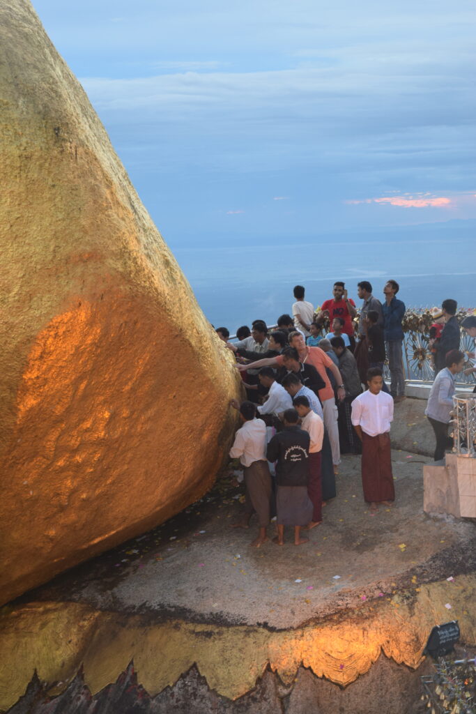 men touching Golden Rock on Thadingyut